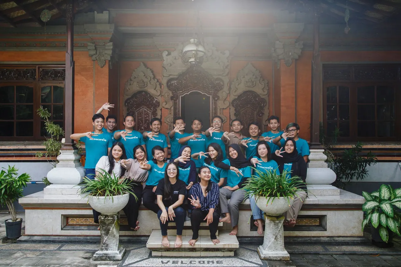 Tim Farmacare berfoto bersama dengan kaos teal di depan bangunan bergaya Bali